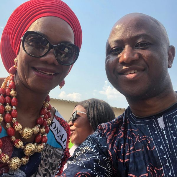 Two smiling people in vibrant traditional attire taking a selfie outdoors.