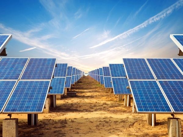 Rows of solar panels under a clear blue sky in a solar farm.