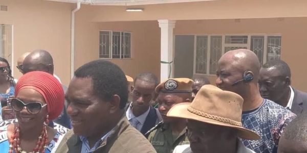 Group of people, some in traditional attire and security personnel, gathered outside a building.